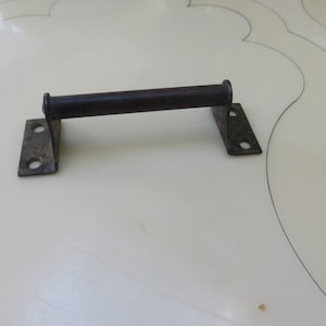 May include: A black metal door handle with two rectangular plates on either side of the handle. The handle is attached to the plates with two screws on each side.
