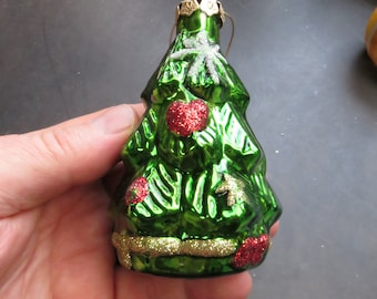 May include: A green glass Christmas tree ornament with red glitter accents and a gold glitter trim. The ornament has a white snowflake design on the front.