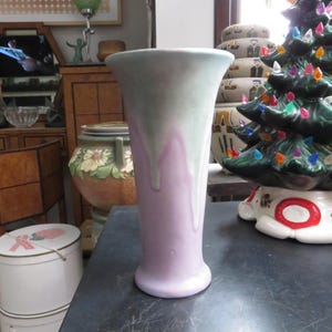 May include: A tall, pastel-colored ceramic vase with a flared top. The vase features a gradient of colors, with a light green and lavender drip design. The vase is likely for decorative purposes.