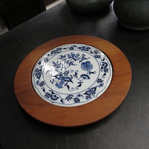 May include: A wooden plate with a blue and white porcelain plate inset. The porcelain plate features a floral design.