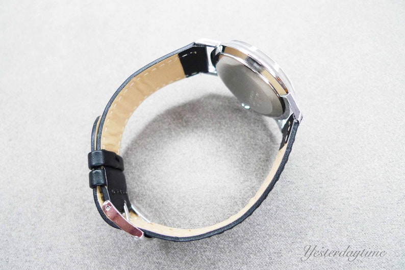 May include: A silver wristwatch with a black leather band. The watch face is not visible.