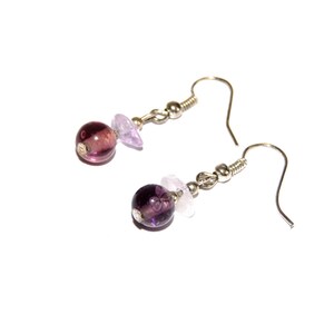May include: A pair of silver dangle earrings with purple and light purple glass beads.
