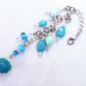 May include: A silver chain charm bracelet with a turquoise blue charm and several smaller turquoise and light blue beads.