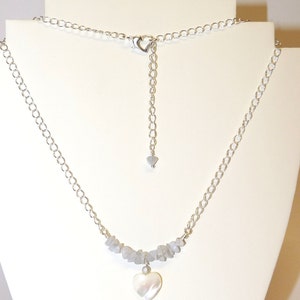 May include: A silver chain necklace with a silver heart charm and a row of gray stones. The necklace has an adjustable length.