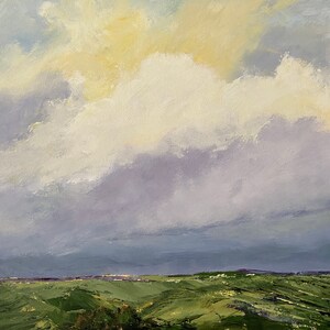 May include: A painting of a landscape with a large, fluffy white cloud in a blue sky. The sky is a light blue with a hint of purple. The cloud is in the center of the image and is casting a shadow on the ground. The ground is a green field with rolling hills.