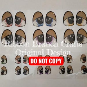 May include: A sheet of various cartoon eye stickers with brown, green, pink, and blue irises. The stickers have a brown upper eyelid and a white lower eyelid. The text "Ribbon Branch Crafts Original Design" and "DO NOT COPY" are visible.