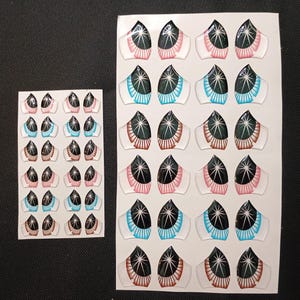 May include: Two sheets of clear stickers featuring various eye designs. The eyes have black pupils with white starbursts, and are outlined with pink, brown, and blue. The stickers are likely for crafts or scrapbooking.
