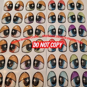 May include: A sheet of cartoon eye stickers in various colours. Each eye has a unique design with shades of orange, blue, green, and purple. The stickers have a white background and a black star in the center. Text on the sheet reads "Ribbon Branch Crafts" and "DO NOT COPY".