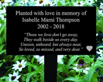 May include: Black metal garden memorial plaque with white text. The plaque reads "Planted with love in memory of Isabelle Marni Thompson 2002-2018" and a quote: "Those we love don't go away, They walk beside us every day. Unseen, unheard, but always near, So loved, so missed, and very dear."