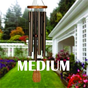 May include: A medium-sized wind chime with black and gold tubes hanging from a wooden frame. The wind chime is hanging in a garden setting with flowers and greenery in the background.