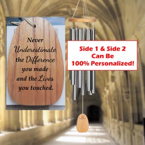 May include: Wooden wind chime with silver-colored tubes and a wooden oval-shaped pendant. The chime has a wooden top and bottom piece. A wooden tag displays the text: "Never Underestimate the Difference you made and the Lives you touched."