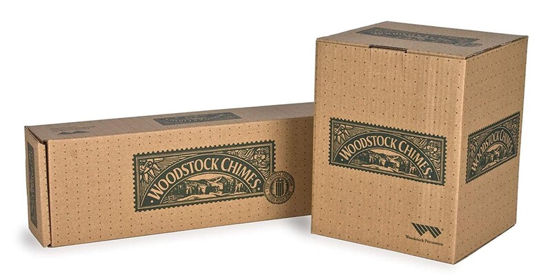 Pu&ograve; includere: Due scatole di cartone con la scritta "Woodstock Chimes" stampata su di esse. Le scatole sono marroni con testo verde e un'immagine verde di una casa e alberi. La scatola pi&ugrave; piccola &egrave; sdraiata sul lato e la scatola pi&ugrave; grande &egrave; in piedi.