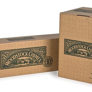 May include: Two cardboard boxes with the text "Woodstock Chimes" printed on them. The boxes are brown with green text and a green image of a house and trees. The smaller box has a green logo with the text "Woodstock Percussion" printed on it.