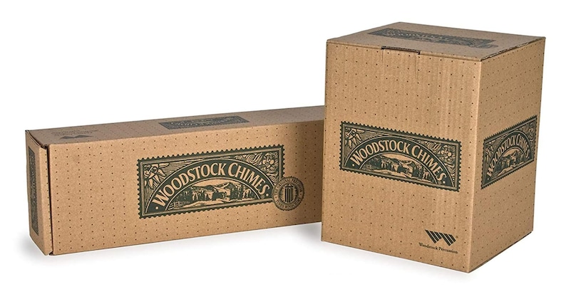May include: Two cardboard boxes with the text "Woodstock Chimes" printed on them. The boxes are brown with green text and a green image of a house and trees. The smaller box has a green logo with the text "Woodstock Percussion" printed on it.