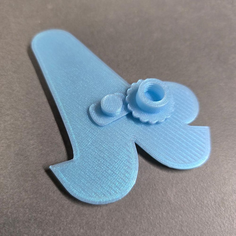 May include: A light blue plastic 3D printed object shaped like a letter A with two small round knobs attached to it.