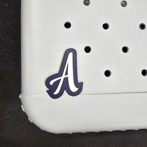 May include: A white plastic tote bag with a navy blue letter A sticker on the front.