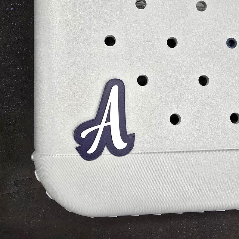 May include: A white plastic tote bag with a navy blue letter A sticker on the front.