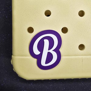 May include: A yellow shoe with a purple and white letter "B" charm.