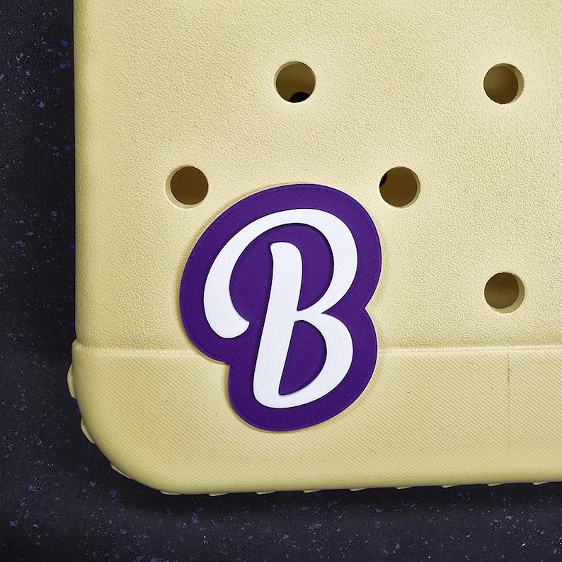 May include: A yellow shoe with a purple and white letter "B" charm.
