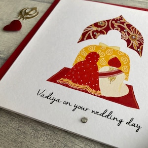 Close up view of the Anand Karaj Sikh wedding card. Illustration shows the Sikh couple sitting before the Guru Granth Sahib (Sikh Holy Book) Front is printed with, Vadiya (congratulations) on your wedding day.