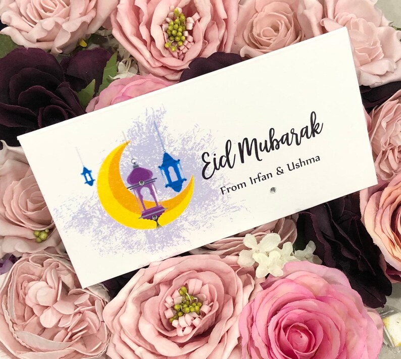 Personalised Eid Mubarak envelopes with a moon and lantern design printed onto white quality 300gsm card. Front reads Eid Mubarak with name/s of person gifting. Finished with diamante for extra sparkle.