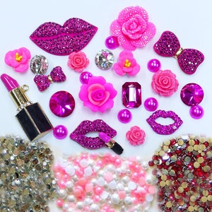 Puede incluir: Surtido de adornos de strass rosa y dorado, que incluyen labios, flores, lazos y un dije de lápiz labial. También se incluyen bolsas de cuentas de perlas rosa y doradas, y diamantes de imitación rojos y dorados.