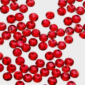 May include: A scattering of small, round, red rhinestones on a white background.