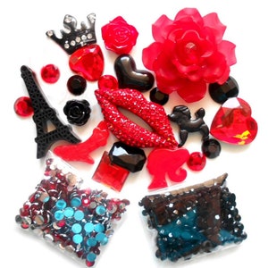 Puede incluir: Una colección de adornos de resina roja y negra, que incluye una corona, labios, la Torre Eiffel, una rosa, un corazón y un caniche. Se incluyen dos bolsas de diamantes de imitación, una con diamantes de imitación rojos y azules y otra con diamantes de imitación negros.