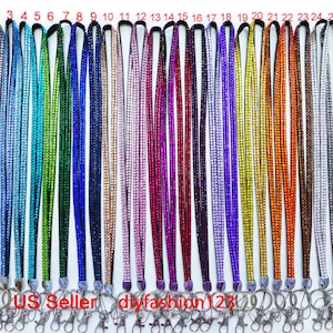 May include: Twenty-seven colorful rhinestone lanyards with silver swivel clasps. The lanyards are arranged in a row, numbered 1 through 27.