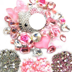 Puede incluir: Surtido de pedrería rosa y plateada, perlas y purpurina. La pedrería tiene varias formas, incluyendo corazones, óvalos y lágrimas. También hay un gran dije de Hello Kitty plateado.
