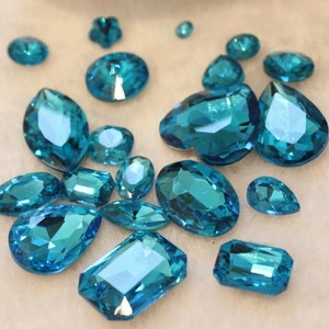 May include: Assortment of teal blue crystal rhinestones of various shapes and sizes.
