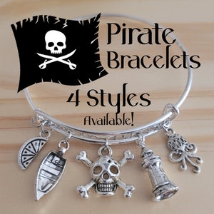 May include: Silver charm bracelet with four different pirate-themed charms: a skull and crossbones, a ship, a lighthouse, and an octopus. The bracelet is on a wooden surface and the text "Pirate Bracelets 4 Styles Available!" is visible above the bracelet.