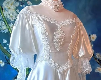 May include: A white satin dress featuring a high lace collar with a central oval brooch, sheer yoke, and puff sleeves. The bodice is adorned with intricate white floral embroidery and lace trim, extending from the neckline to the waist.