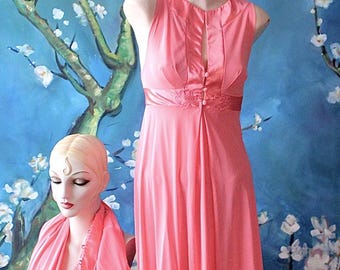 May include: A vintage pink nightgown and robe set displayed on mannequins. The sleeveless nightgown features a high neckline, decorative buttons, and a satin ribbon detail. The matching robe is draped over a second mannequin. The background is a blue mural with white flowers.
