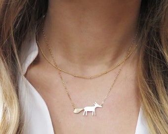 Puede incluir: Un collar de oro con una cadena delicada y un colgante de zorro. El zorro está mirando hacia la derecha y tiene una cola larga y delgada.