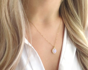 May include: A gold chain necklace with a round, iridescent moonstone pendant.