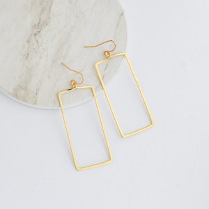 May include: A pair of gold-toned rectangle shaped earrings with a simple design.