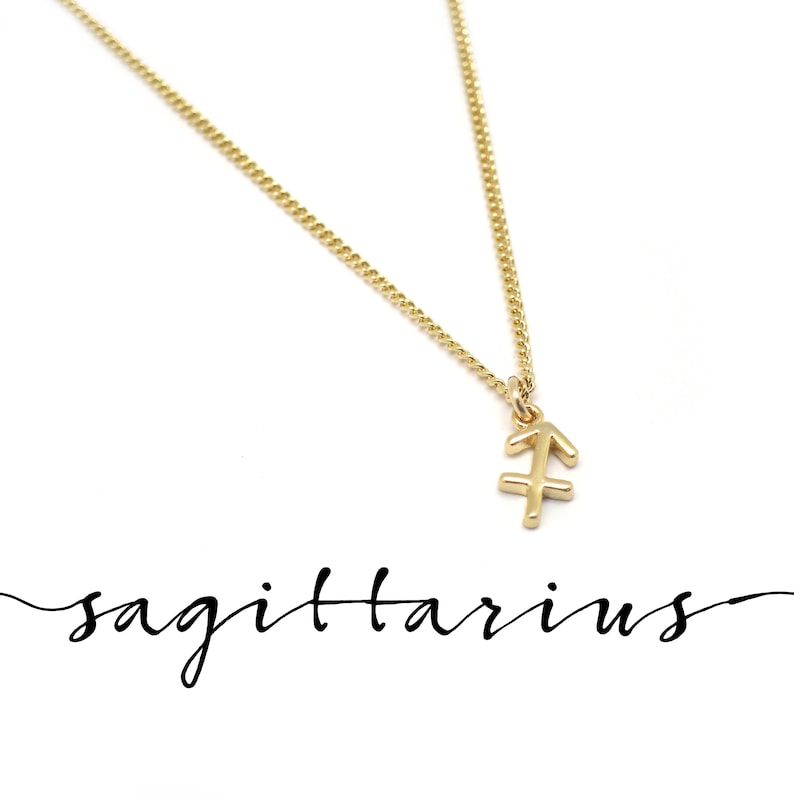 Peut inclure: Un collier en cha&icirc;ne dor&eacute;e avec un petit pendentif en or repr&eacute;sentant le symbole du zodiaque Sagittaire. Le mot "sagittaire" est &eacute;crit en cursive sous le pendentif.
