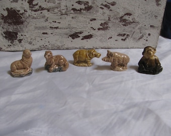 Może przedstawiać: Pięć małych ceramicznych figurek zwierząt. Brązowa foka, brązowa wydra, brązowy hipopotam, brązowa świnia i brązowa małpa.