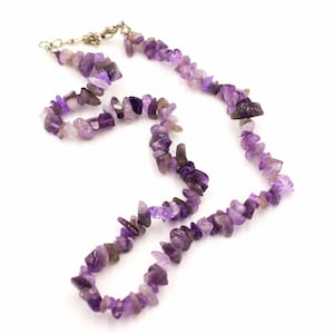 May include: A purple amethyst gemstone necklace with a silver clasp. The necklace is made of small, irregular shaped stones.