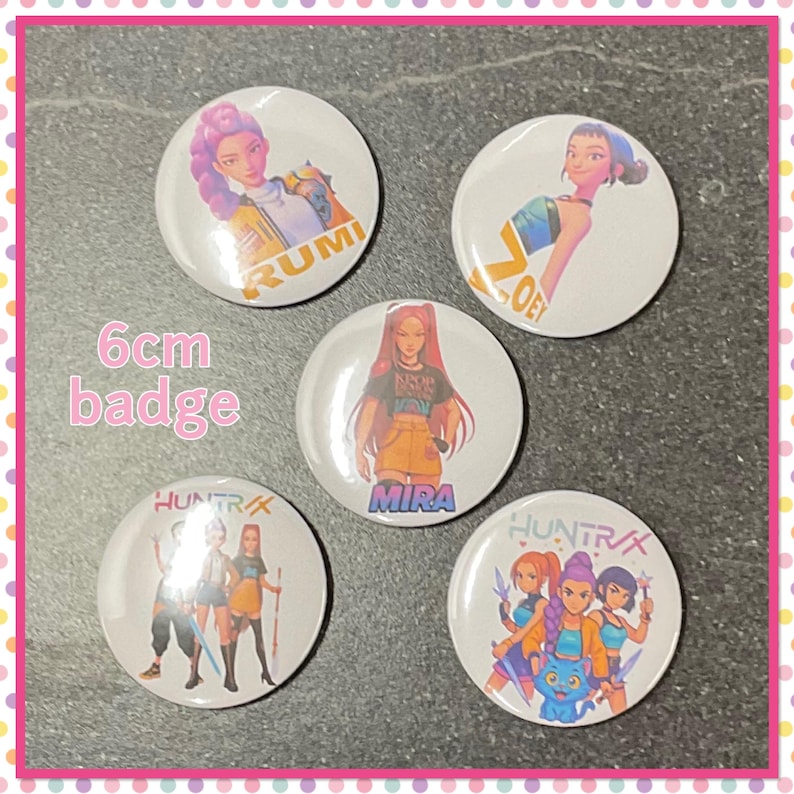 Op de afbeelding: Vijf witte, ronde 6 cm badges met kleurrijke illustraties van anime-achtige personages. Elke badge heeft een ander karakterontwerp, met namen als RUMI, ZOE en MIRA. De tekst "HUNTR/X" is ook zichtbaar op sommige badges.