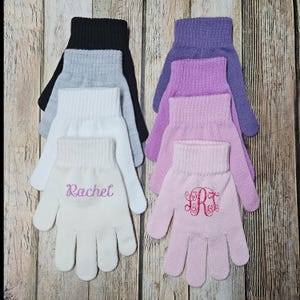 May include: A collection of knitted gloves in various colors including black, gray, white, purple, and light pink. The white glove features the name Rachel embroidered in pink, while the light pink glove displays a pink embroidered monogram.