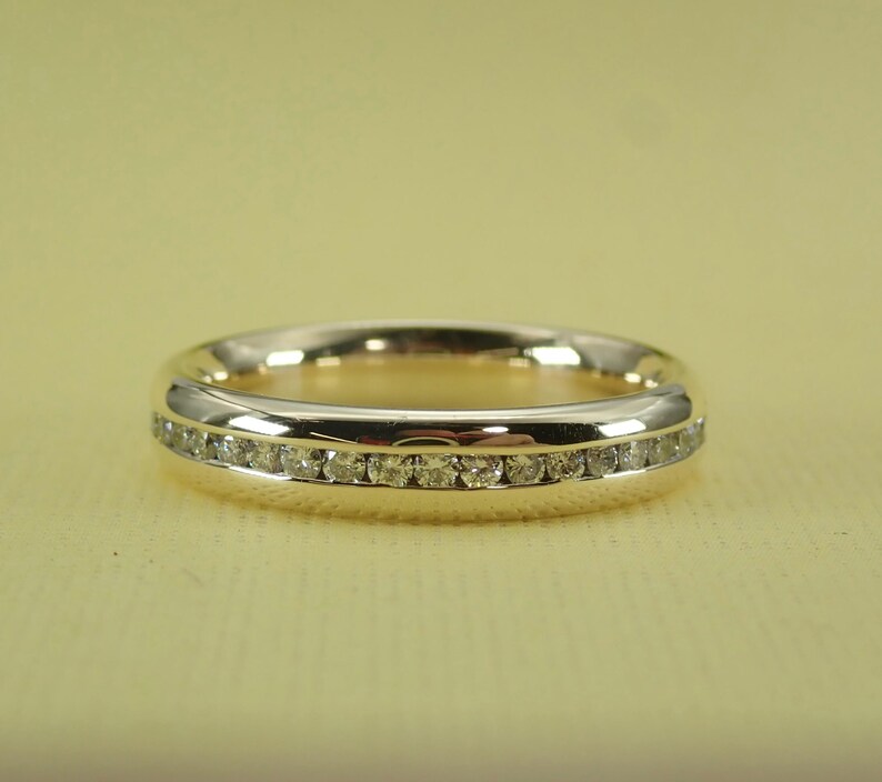 May include: A gold band ring with a single row of small diamonds set in a channel setting.