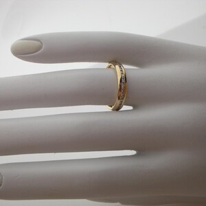 May include: A gold band ring with a row of small diamonds set in the band.