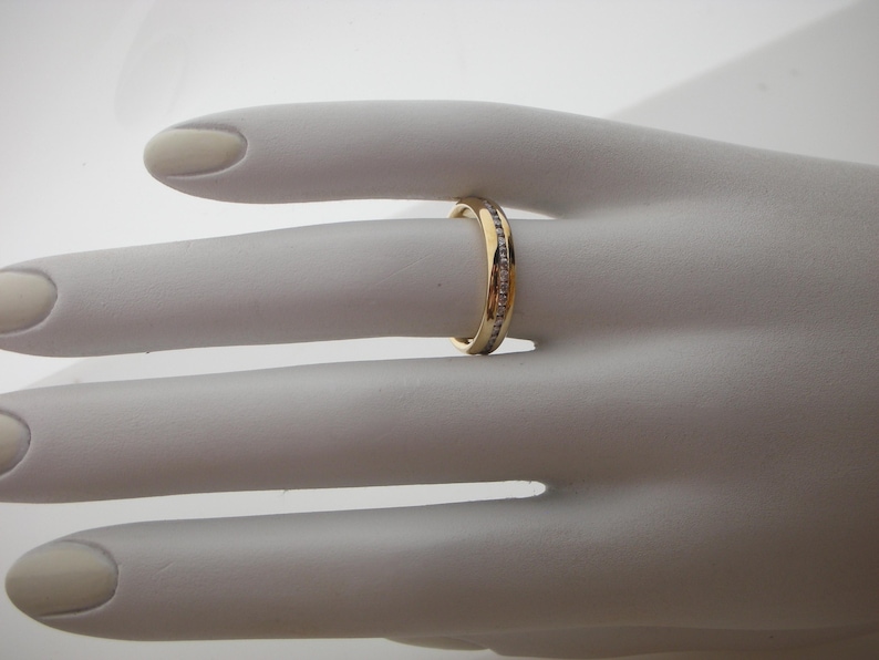 May include: A gold band ring with a row of small diamonds set in the band.