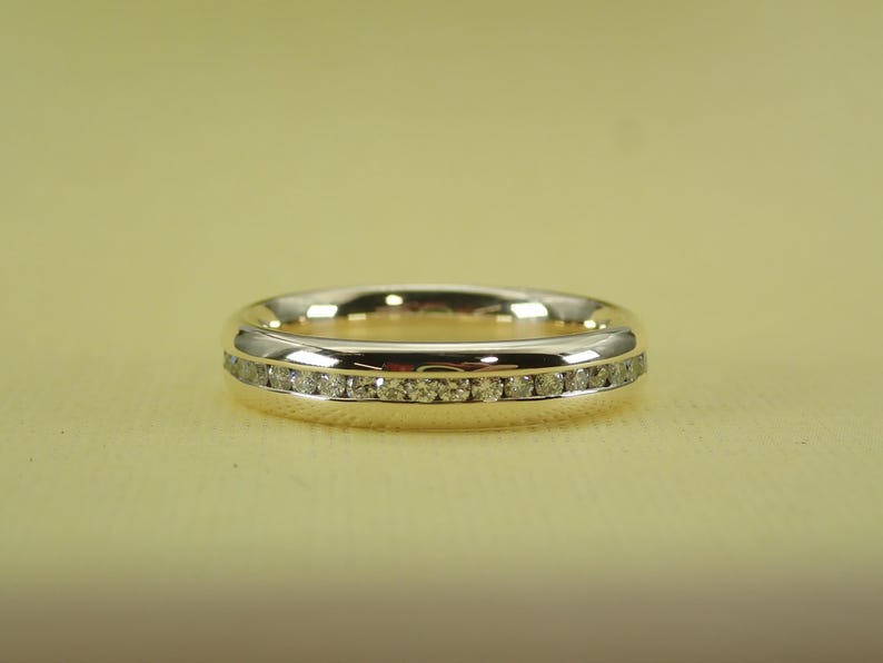 May include: A gold band with a row of small diamonds set in a white metal.