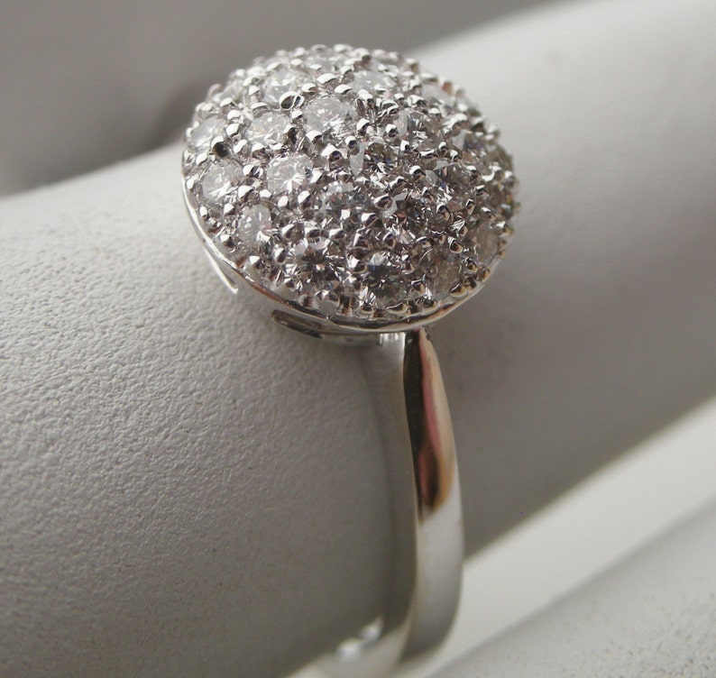 May include: A silver ring with a round, pave-set diamond top.