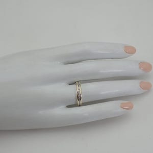 May include: A thin silver band with a row of small diamonds set into the band.