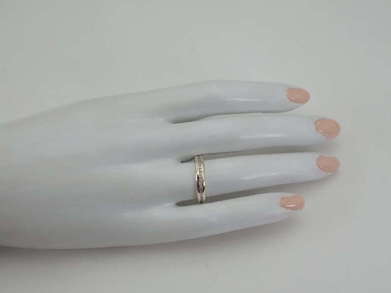 May include: A thin silver band with a row of small diamonds set into the band.