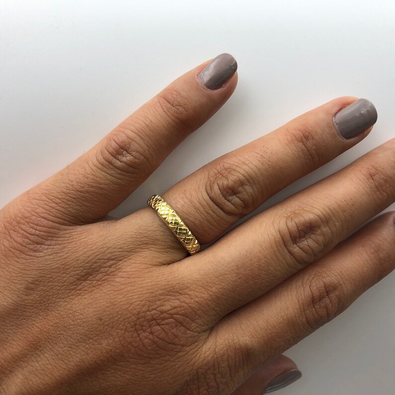 Puede incluir: Un anillo de banda de oro con un dise&ntilde;o tejido texturizado.